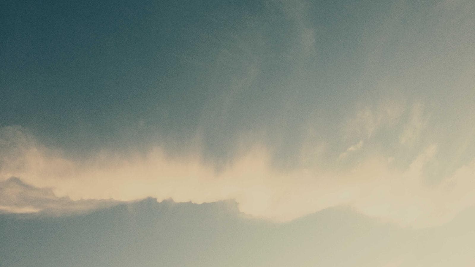 A cloudy sky with shades of blue and cream, showing a light cloud formation stretching horizontally across the middle.